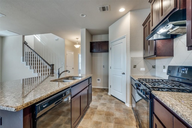 kitchen with sink, light stone counters, an island with sink, decorative backsplash, and black appliances