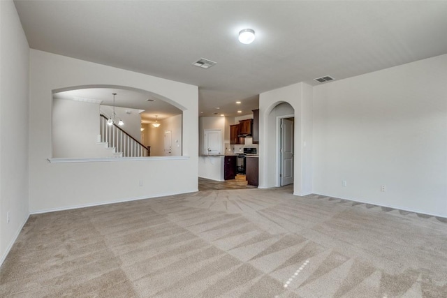 unfurnished living room featuring light colored carpet and a chandelier