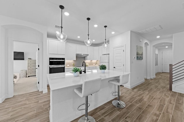 125 Jasmine Ln, Marble Falls, TX 78654 - kitchen with freestanding refrigerator, arched walkways, light wood-type flooring, recessed lighting, and white cabinets