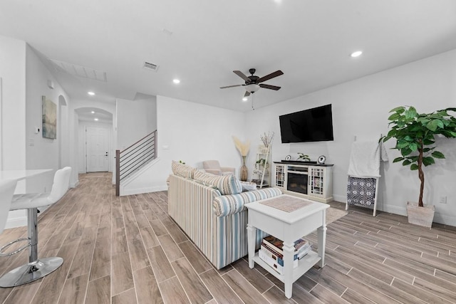 living room featuring light hardwood / wood-style flooring, a fireplace, and ceiling fan