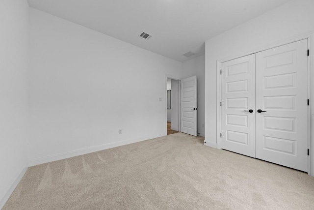 unfurnished bedroom featuring light carpet and a closet