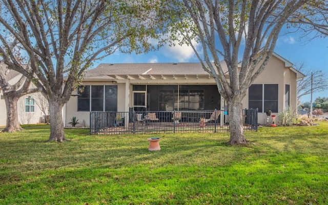 rear view of house featuring a sunroom and a lawn