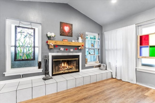 sitting room with vaulted ceiling, a fireplace, and light hardwood / wood-style floors