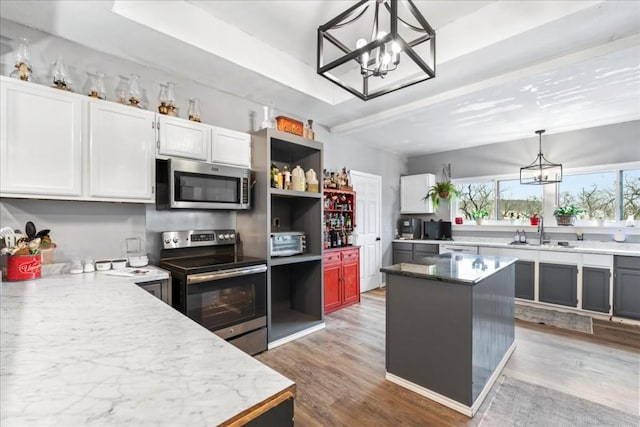 kitchen featuring appliances with stainless steel finishes, pendant lighting, white cabinets, a center island, and an inviting chandelier