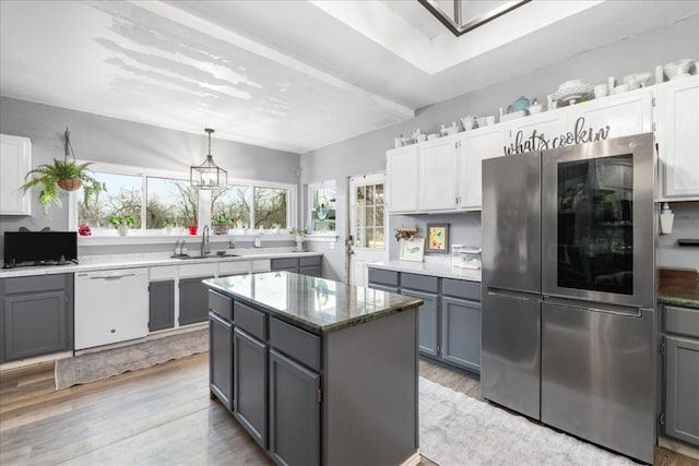 kitchen with gray cabinets, stainless steel refrigerator, dishwasher, sink, and a center island