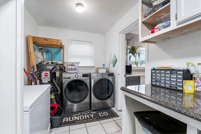 clothes washing area featuring water heater, washing machine and dryer, and light tile patterned floors