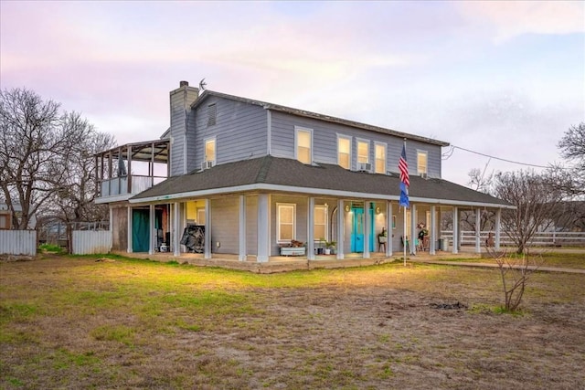 back house at dusk featuring a lawn