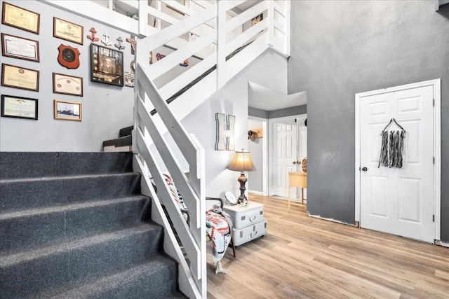 staircase featuring a towering ceiling and wood-type flooring