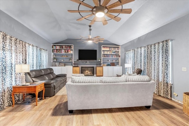 living room with vaulted ceiling, built in features, ceiling fan, and light wood-type flooring