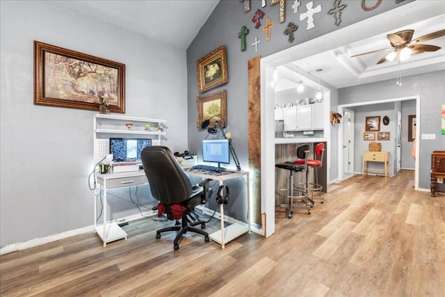 office with ceiling fan, lofted ceiling, a tray ceiling, and light hardwood / wood-style floors