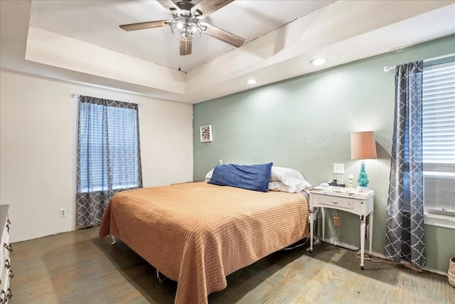 bedroom featuring a raised ceiling, hardwood / wood-style flooring, and ceiling fan