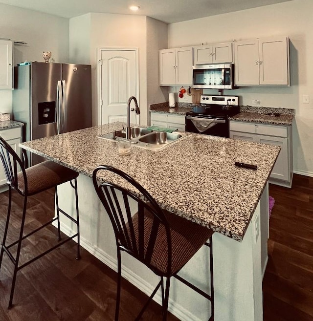 kitchen featuring sink, white cabinetry, a center island with sink, dark hardwood / wood-style flooring, and stainless steel appliances