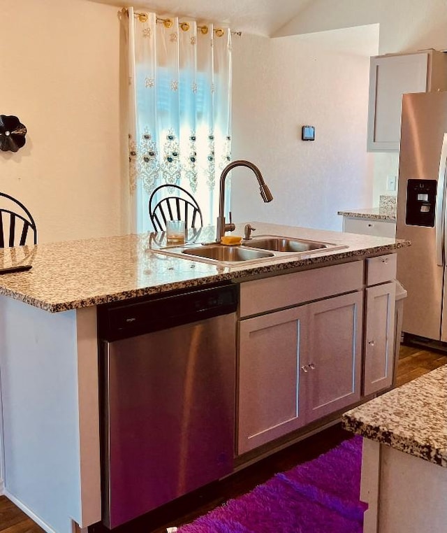 kitchen featuring light stone countertops, appliances with stainless steel finishes, sink, and dark hardwood / wood-style floors