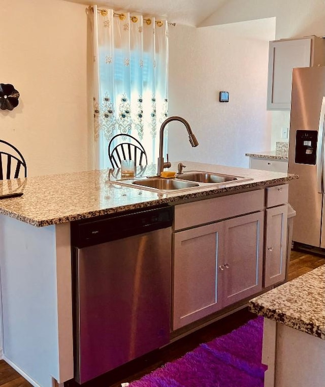 13120 Roving Pass, Elgin, TX 78621 - kitchen featuring stainless steel appliances, a sink, an island with sink, light stone counters, and dark wood-type flooring