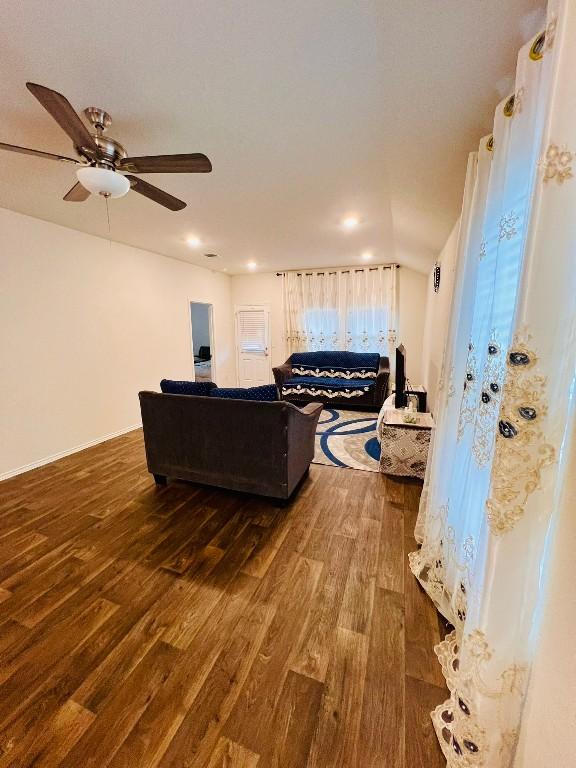 living room featuring dark wood-type flooring and ceiling fan