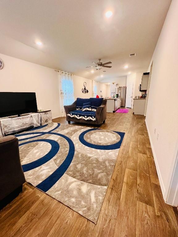 bedroom featuring hardwood / wood-style flooring, stainless steel refrigerator with ice dispenser, and ceiling fan