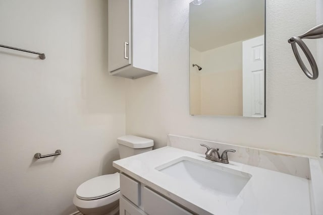 bathroom featuring vanity, walk in shower, and toilet