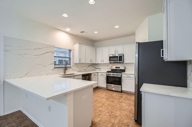 kitchen with sink, white cabinetry, stainless steel appliances, decorative backsplash, and kitchen peninsula