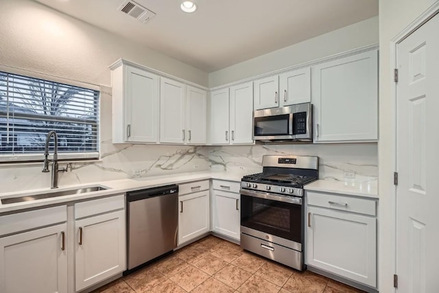 kitchen with sink, white cabinets, decorative backsplash, light tile patterned floors, and stainless steel appliances