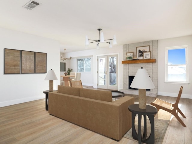 living room featuring a notable chandelier, a wealth of natural light, light hardwood / wood-style flooring, and a fireplace