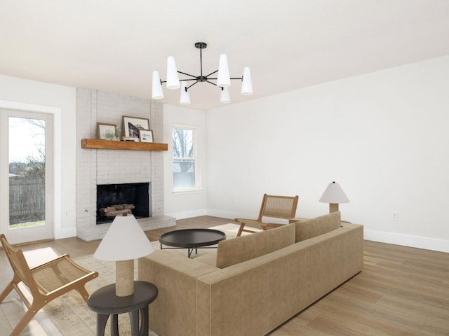 living room with a brick fireplace, a notable chandelier, and light wood-type flooring