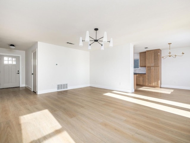 unfurnished living room featuring light wood-type flooring and an inviting chandelier