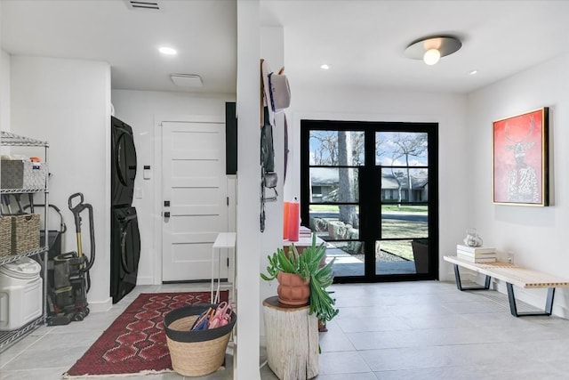 foyer featuring light tile patterned flooring and stacked washer and clothes dryer