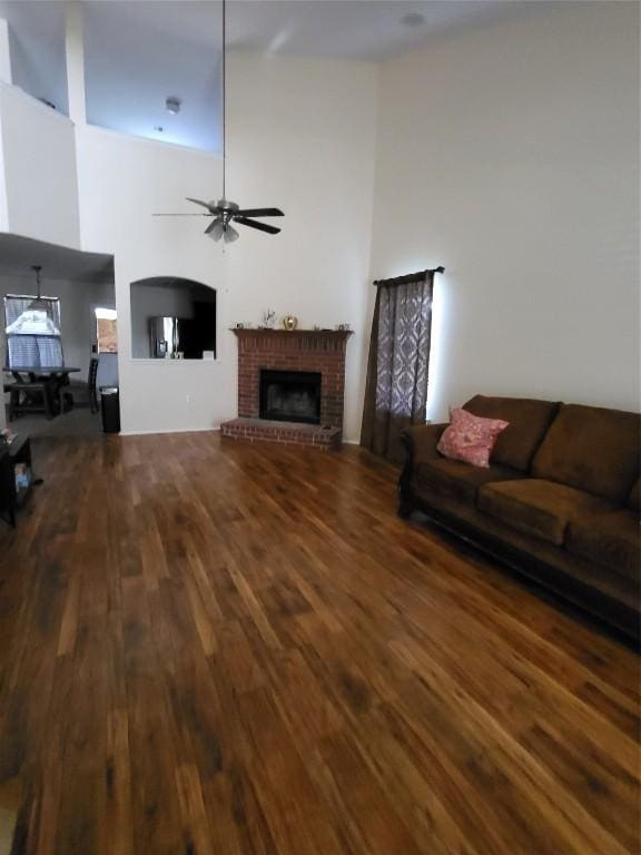 living room featuring ceiling fan, dark hardwood / wood-style floors, and a brick fireplace