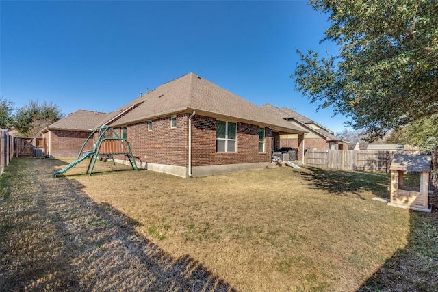 back of property with cooling unit, a yard, and a playground