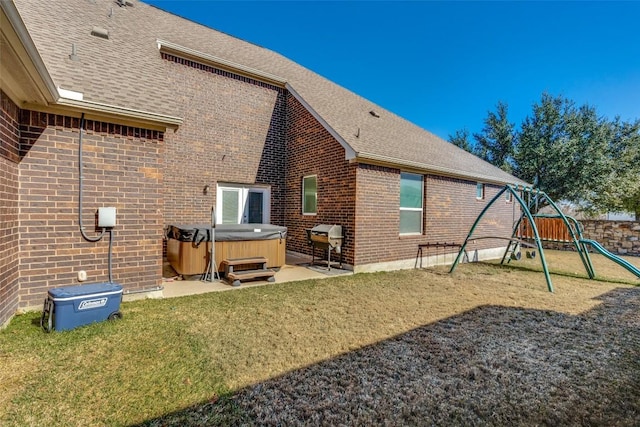 back of property featuring a yard, a hot tub, a patio, and a playground