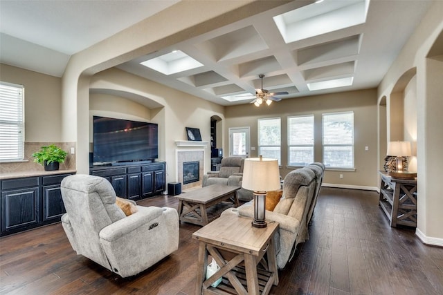 living room featuring dark wood-type flooring, ceiling fan, coffered ceiling, and beam ceiling