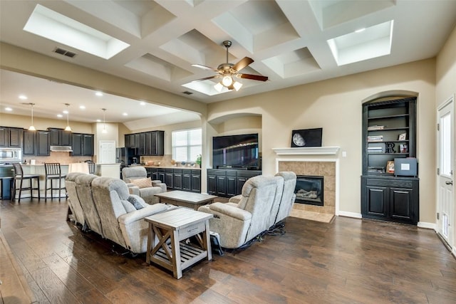 living room featuring a tile fireplace, ceiling fan, beam ceiling, dark hardwood / wood-style floors, and coffered ceiling