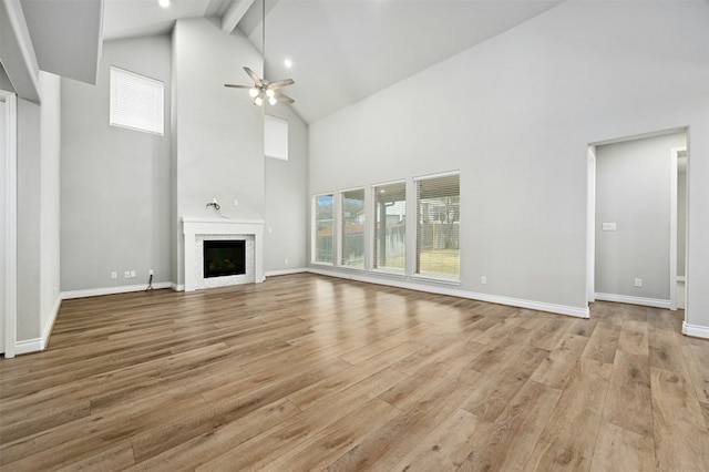 unfurnished living room featuring beamed ceiling, ceiling fan, light wood-type flooring, and high vaulted ceiling