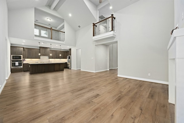 living room with a towering ceiling, hardwood / wood-style floors, and beam ceiling