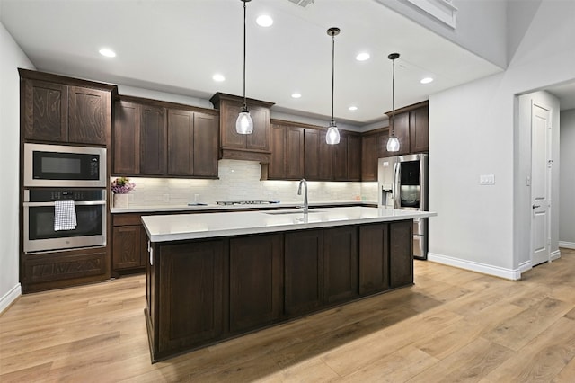 kitchen featuring appliances with stainless steel finishes, dark brown cabinets, pendant lighting, and sink