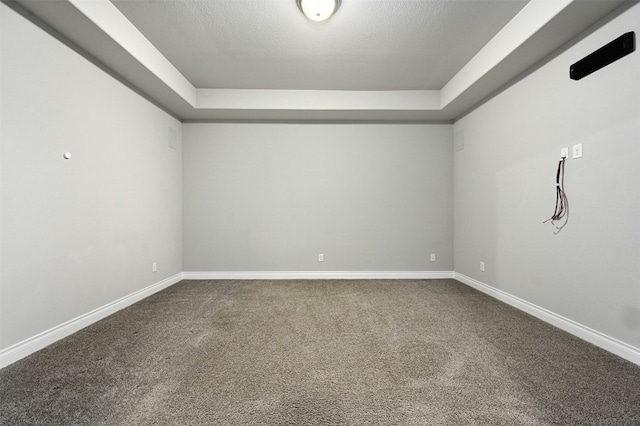 carpeted empty room featuring a raised ceiling