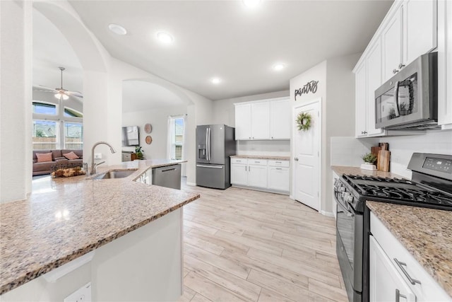 kitchen featuring stainless steel appliances, white cabinetry, light stone countertops, and sink