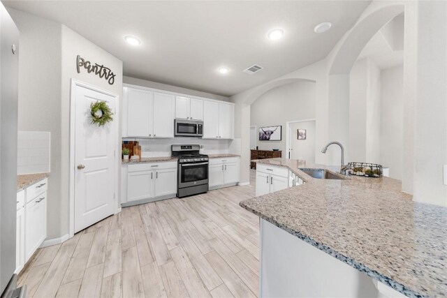 kitchen featuring white cabinetry, sink, light stone countertops, and appliances with stainless steel finishes