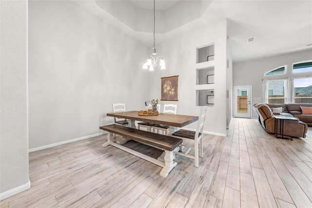 dining space featuring an inviting chandelier, a high ceiling, and light wood-type flooring