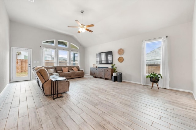 living room featuring a wealth of natural light, vaulted ceiling, ceiling fan, and light wood-type flooring