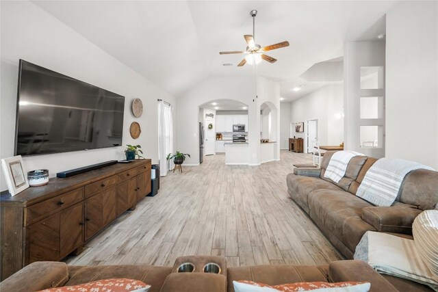 living room with vaulted ceiling, ceiling fan, and light wood-type flooring