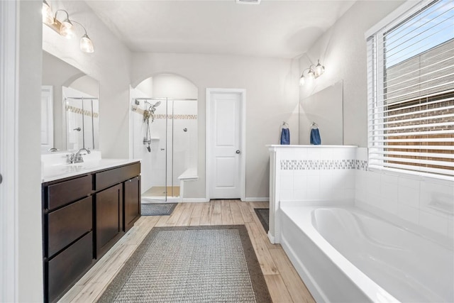 bathroom featuring vanity, hardwood / wood-style flooring, and plus walk in shower