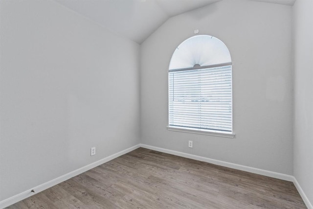 spare room with lofted ceiling and light wood-type flooring