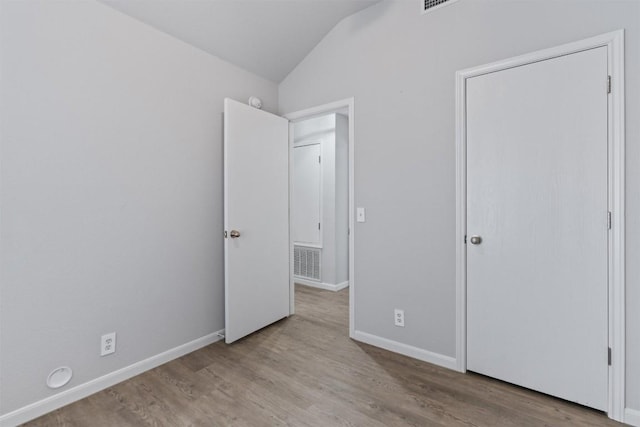 unfurnished bedroom featuring lofted ceiling and light wood-type flooring