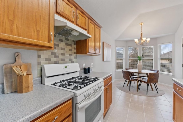 kitchen with lofted ceiling, decorative backsplash, white range with gas cooktop, light tile patterned floors, and a notable chandelier