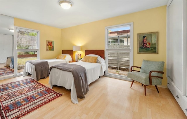 bedroom featuring multiple windows, access to exterior, and light hardwood / wood-style floors