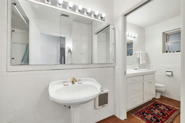 bathroom with double sink, tile walls, and toilet