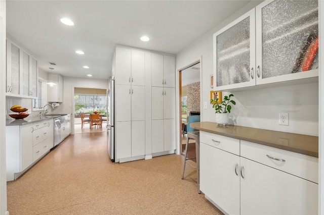 kitchen featuring white cabinetry, hanging light fixtures, sink, and appliances with stainless steel finishes