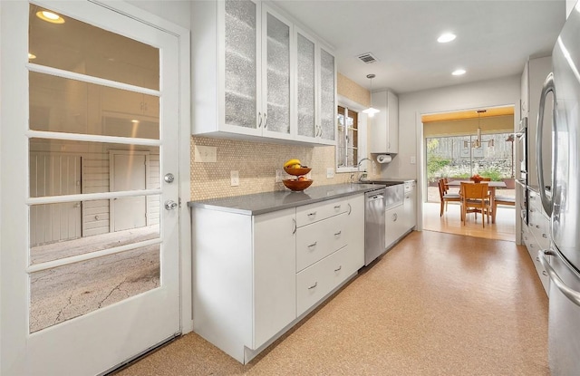 kitchen with sink, tasteful backsplash, decorative light fixtures, stainless steel appliances, and white cabinets