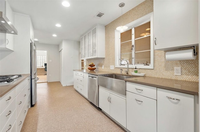 kitchen with sink, white cabinetry, pendant lighting, stainless steel appliances, and wall chimney range hood